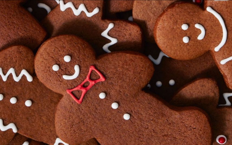 several gingerbread cookies, decorated with white icing to form smiles, eyes, and details. One cookie stands out with a red bow tie,