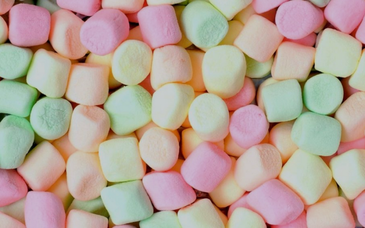 A close-up view of numerous colorful marshmallows in pastel shades of pink, green, yellow, and orange